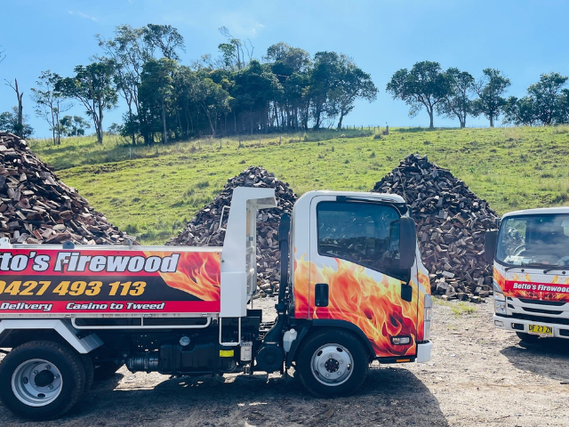 Betto’s Firewood Delivering Mixed & single Species Split Hardwood Firewood. Picture of trucks in lumber yard with firewood piles in background. 800kg, 1000kg, 1500kg to 2000kg load sizes available. All load sizes delivered Free Lismore to Ocean Shores. 1500kg and 2000kg load sizes delivered FREE from Casino & Tweed, Northern Rivers NSW. Every load receives a Free Kindling & Free Firelighters. Bag of free Kindling pictured. Firewood delivered to Ballina, Bangalow, Byron Bay, Brunswick Heads, Alstonville, Clu