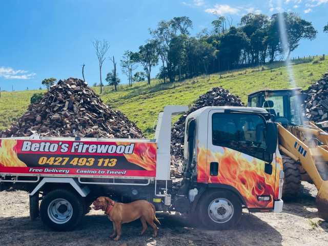 Betto’s Firewood Delivering Mixed & single Species Split Hardwood Firewood. Picture of trucks in lumber yard with firewood piles in background. 800kg, 1000kg, 1500kg to 2000kg load sizes available. All load sizes delivered Free Lismore to Ocean Shores. 1500kg and 2000kg load sizes delivered FREE from Casino & Tweed, Northern Rivers NSW. Every load receives a Free Kindling & Free Firelighters. Bag of free Kindling pictured. Firewood delivered to Ballina, Bangalow, Byron Bay, Brunswick Heads, Alstonville, Clu