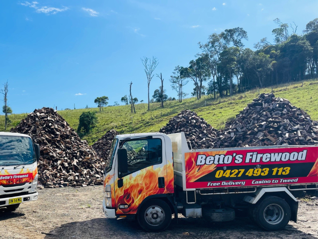 Betto’s Firewood Delivering Mixed & single Species Split Hardwood Firewood. Picture of trucks in lumber yard with firewood piles in background. 800kg, 1000kg, 1500kg to 2000kg load sizes available. All load sizes delivered Free Lismore to Ocean Shores. 1500kg and 2000kg load sizes delivered FREE from Casino & Tweed, Northern Rivers NSW. Every load receives a Free Kindling & Free Firelighters. Bag of free Kindling pictured. Firewood delivered to Ballina, Bangalow, Byron Bay, Brunswick Heads, Alstonville, Clu