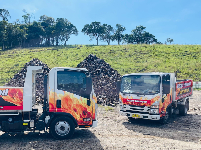 Betto’s Firewood Delivering Mixed & single Species Split Hardwood Firewood. Picture of trucks in lumber yard with firewood piles in background. 800kg, 1000kg, 1500kg to 2000kg load sizes available. All load sizes delivered Free Lismore to Ocean Shores. 1500kg and 2000kg load sizes delivered FREE from Casino & Tweed, Northern Rivers NSW. Every load receives a Free Kindling & Free Firelighters. Bag of free Kindling pictured. Firewood delivered to Ballina, Bangalow, Byron Bay, Brunswick Heads, Alstonville, Clu